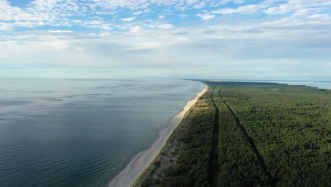 AERIAL:-Rotating-Shot-of-Green-Forest-Cloudy-Sky-and-Rippling-Baltic-Sea-in-Nida