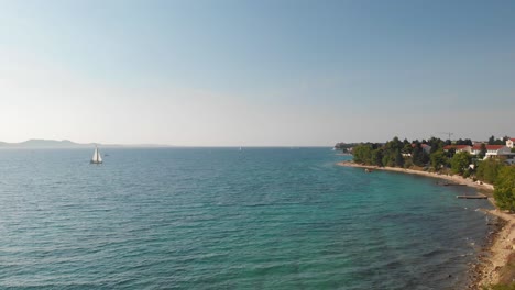 Día-Soleado-Sobre-La-Playa-De-La-Ciudad-De-Zadar-Y-El-Paseo-Costero-Con-Vistas-Al-Mar-Adriático-Y-Al-Velero