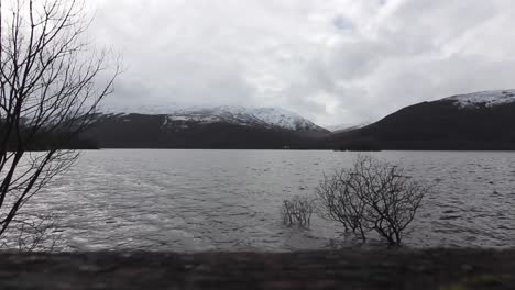 Time-Lapse-lake-and-clouds-in-the-highlands-of-Scotland,-snowy-mountains-at-the-background,-winter-season,-static-shot