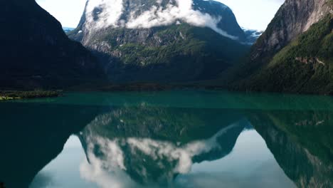 Reflejo-De-Cristal-En-La-Superficie-De-Un-Lago-Prístino-Rodeado-De-Altas-Montañas-En-Noruega-Tiro-En-Movimiento