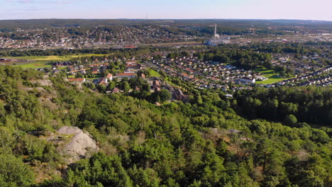 Scenic-aerial-drone-view-of-Swedish-mountain-hill-green-forest-with-residential-suburb-in-background,-east-of-Gothenburg,-Sweden,-day,-forward