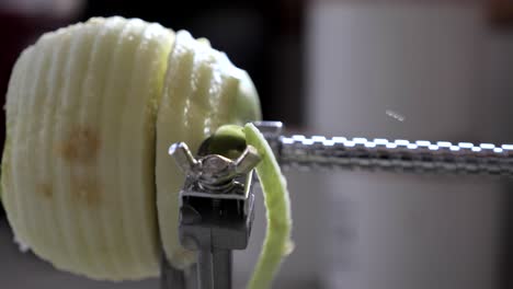 Slow-motion-metal-kitchen-device-peeling,-cutting-and-core-green-juicy-apple-skin-and-flesh-on-kitchen-bench