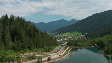 aerial-view-of-Gosau-in-Austria-behind-trees-and-lake-and-mountains-in-the-back