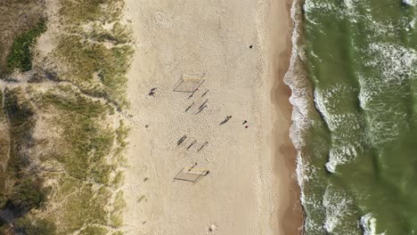 AERIAL:-Top-View-Shot-of-Football-Players-Shadows-on-a-Sandy-Beach