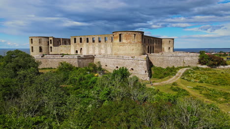 Panoramic-View-Of-Borgholm-Castle-Ruins-Nestled-In-Lush-Green-Field-Under-Blue-Cloudy-Sky-In-Borgholm,-Öland,-Sweden---Wide-Shot-Pan-Left