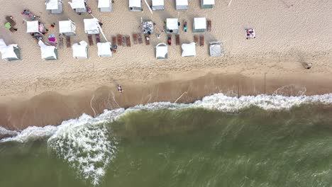 AERIAL:-Top-Shot-of-Waving-White-Tents-and-Flags-on-a-Sandy-Beach-nera-Baltic-Sea
