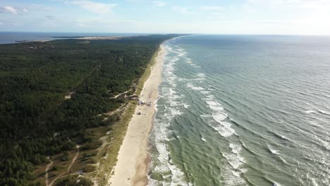 AERIAL:-Flying-Backwards-Above-Majestic-Nida-Beach-with-Forest-and-Sea