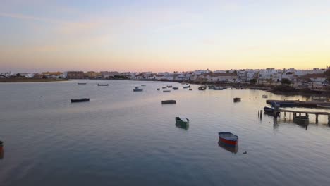Low-aerial-shot-over-fishing-boats-near-white-houses-in-Barbate,-Cadiz