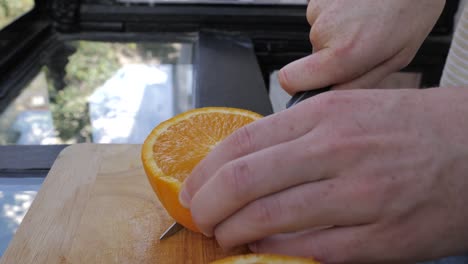 Young-male-slices-in-orange-in-bright-Kitchen