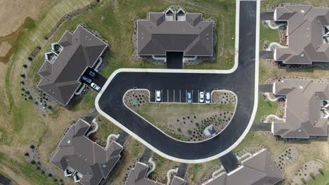 Top-down-aerial-birds-eye-overhead-perspective,-new-home-condo-apartment-construction,-brown-roof,-new-landscape-and-recently-planted-grass,-cars-parked-in-community-retirement-home,-senior-citizen