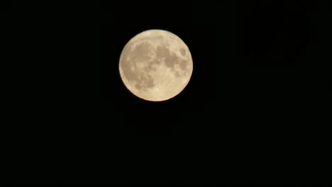 Full-harvest-moon-crater-orange-surface-closeup-passing-across-dark-sky