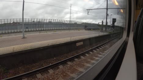 POV-shot-of-platform-through-train's-window-which-slowly-depart-from-train-station