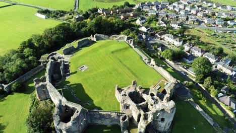 Historic-British-landmark-Denbigh-Castle-medieval-old-hill-monument-ruin-tourist-attraction-aerial-tilt-up-view-across-countryside