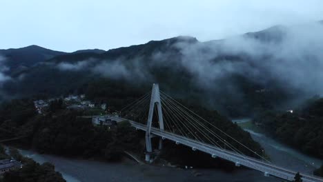 High-Aerial-Drone-over-creepy-rural-fog-valley-at-dusk-with-bridge-and-ravine---forwards-flight