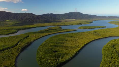 Daintree-River-delta-meandering-through-rainforest,-boats-on-water,-aerial-view