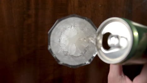 Female-hand-pouring-beer-into-glass-with-ice-cubes
