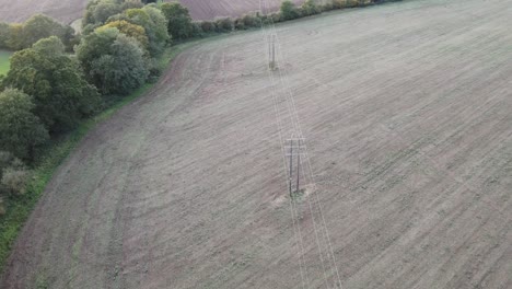 Stromleitungen-In-Ackerland-Im-Vereinigten-Königreich-Drohne-Fliegt-Entlang-Des-Weges-Von-Leitungen,-Die-Im-Spätsommer-Durch-Bäume-Führen