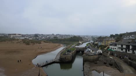 Bude-Cornwall-Canal-and-Lock-Aerial-4K-footage-people-cross-small-bridge-Drone-along-canal-passing-boat-moored