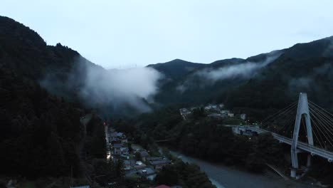 High-Aerial-Drone-over-creepy-fog-valley-at-dusk-with-ravine-and-bridge