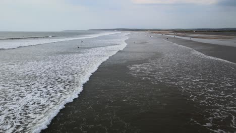 Westward-ho-beach-Devon-drone-flying-along-huge-beach-surfers-in-background