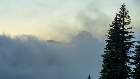 Zeitraffer-Von-Wolkenwellen,-Die-Bei-Sonnenaufgang-In-Einem-Tal-Unter-Dem-Berggipfel-Fließen