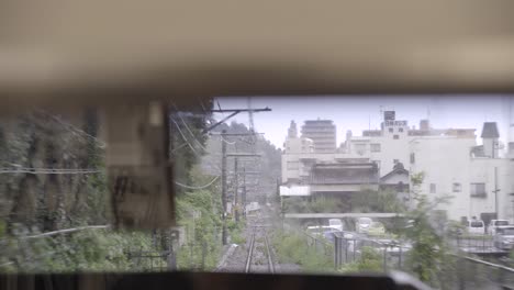View-out-of-back-of-train-window-on-tracks,-shaking-as-train-is-driving-fast-in-city