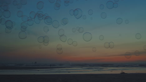 Bubbles-float-past-as-sun-sets-on-vast-empty-beach,-wide