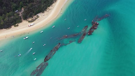 Aerial:-Tangalooma-shipwrecks-beached-in-turquoise-Australia-sea,-Moreton-Island