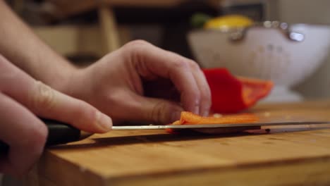 Chef-slices-big-red-pepper-on-the-cutting-board,-in-the-kitchen