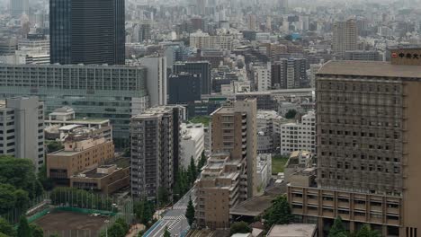 High-above-timelapse-of-Tokyo-skyline-with-skyscrapers-in-distance-and-traffic---tilt-up-shot