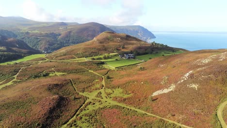 Rural-Welsh-heather-covered-mountain-hillside-valley-ocean-coastline-left-aerial-orbit-view
