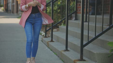 Cropped-Image-Of-A-Female-Model-Dressed-In-Blue-Jeans-And-Pink-Single-Button-Blazer-Standing-Outside-The-Building---Slow-Motion