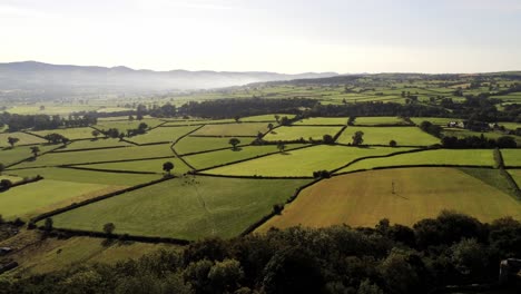 Beautiful-misty-Welsh-countryside-rural-patchwork-sunrise-landscape-aerial-view-right-pan
