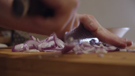 Chopping-onion-with-sharp-knife-on-a-cut-board
