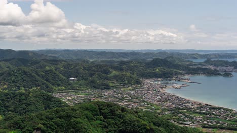 Wide-open-timelapse-over-small-ocean-town-with-rolling-hills,-ocean-and-clouds---Push-in-shot