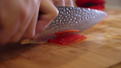 Chef-slices-big-red-pepper-on-the-cutting-board,-in-the-kitchen