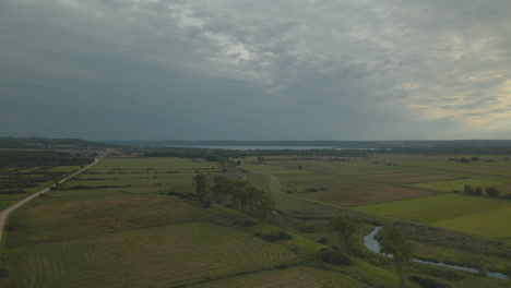 Aerial-flight-over-beautiful-flat-scenic-farmland-in-rural-Debki-Poland-with-river