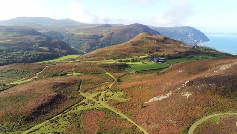 Rural-Welsh-heather-covered-mountain-hillside-valley-ocean-coastline-orbit-right-aerial-view