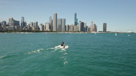 Drone-Flies-Behind-Yacht,-Pan-Left-to-Reveal-Chicago-Skyline-on-Beautiful-Summer-Day