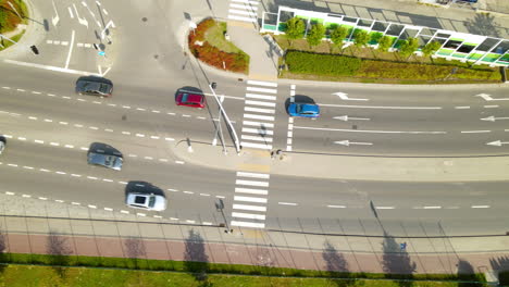 Aerial-view-of-cars-starting-at-traffic-stop-light-driving-along-highway-road-lanes