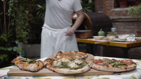 Chef-puts-freshly-baked-pizza-from-tray-onto-the-table