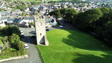 Medieval-St-Hilarys-tower-Denbighshire-Welsh-residential-village-North-Wales-aerial-view-descending-tilt-up-across-countryside-horizon