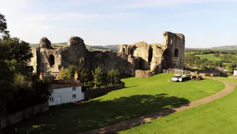 Historic-ancient-Welsh-landmark-Denbigh-Castle-medieval-old-hill-monument-ruin-tourist-attraction-aerial-rising-reveal-view-across-countryisde