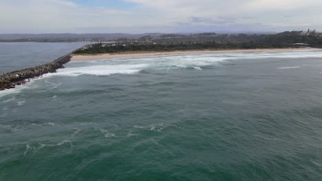 Ondulante-Mar-Azul-Con-Olas-Rompiendo-En-El-Malecón---Playa-De-Sharpes-En-Skennars-Head---Nsw,-Australia---Drone-Aéreo