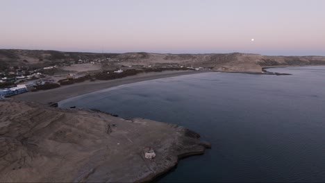 Beautiful-scenery-with-town-facing-the-sea-at-sunset-while-moon-is-rising---Aerial-wide-shot