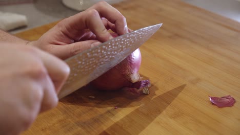 Cutting-onion-with-sharp-knife-on-a-cut-board