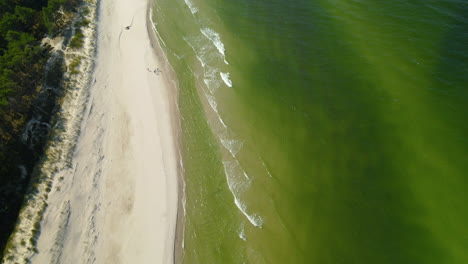 Green-Tides-Crashing-In-White-Sand-Beach-In-Osetnik-Poland---aerial-shot