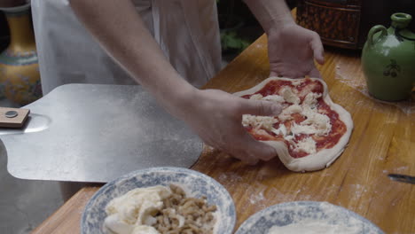 Chef-slides-formed-Neapolitan-pizza-dough-pizza-onto-??