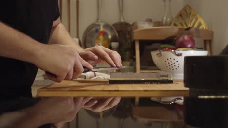 Chef-sharpens-knife-on-the-sharping-stone-on-the-kitchen-table