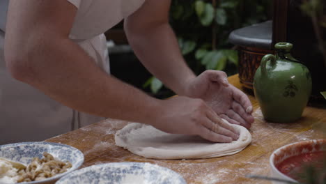 Chef-stretches-and-forms-the-pizza-dough-into-a-circle-on-a-wooden-cooking-table